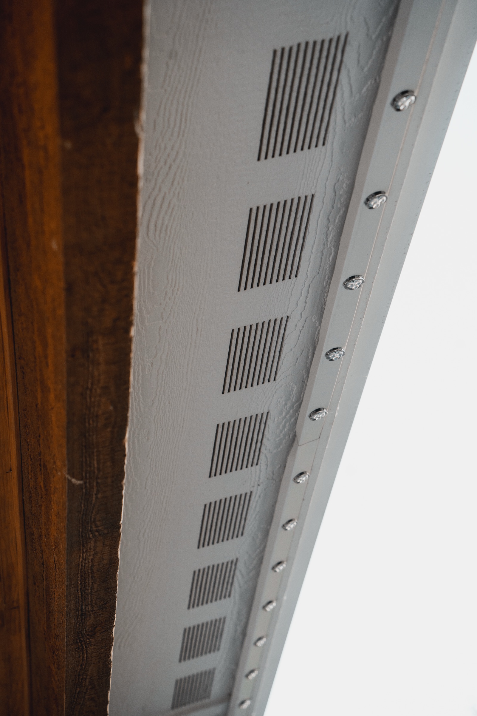 Close-up of color-matched soffit track with LED mounting points in daylight