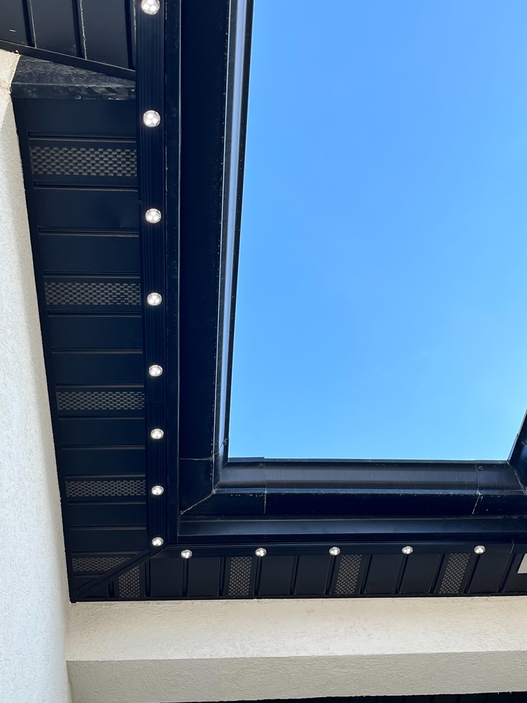 Close-up of the color-matched black channel and low-profile LED points tucked along a fascia in daylight
