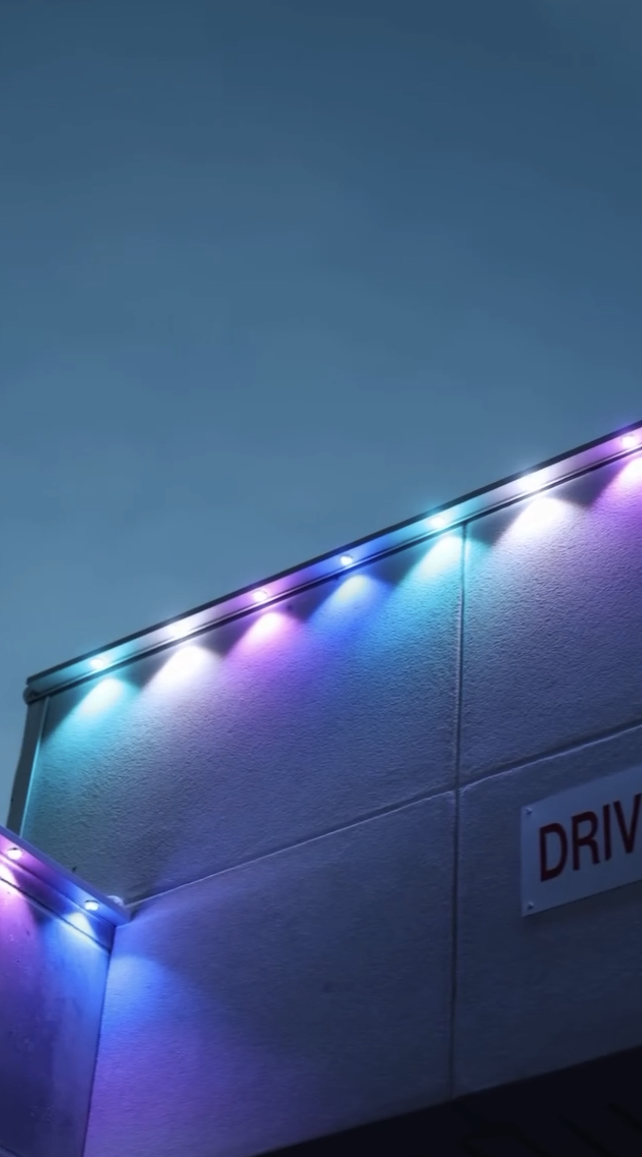 Close-up of colorful purple and blue LED points along a roofline at dusk